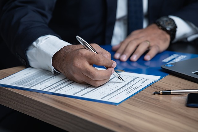 Man filling out a form with a silver pen.